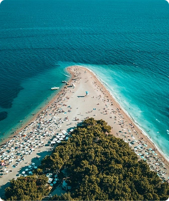Aerial view of Zlatni Rat beach near Bol, Croatia, a top destination on Brač Island, popular for Split boat tours, with a V-shaped pebble shoreline, turquoise Adriatic waters, and lush pine trees.