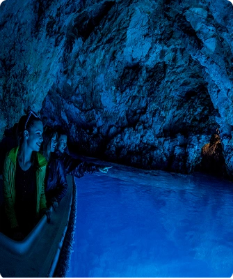 Tourists exploring the famous Blue Cave on Biševo Island, near Split, Croatia, during a Split boat day tour; vibrant blue light reflecting off the Adriatic Sea waters inside the rocky cave.